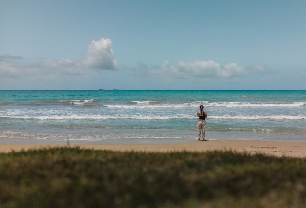 Un hombre parado en la cima de una playa de arena junto al océano