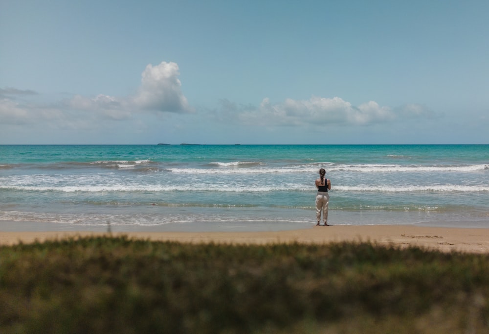 a man standing on top of a sandy beach next to the ocean