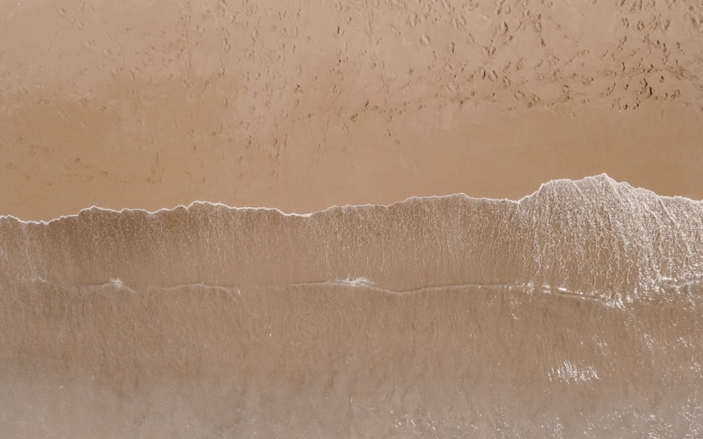 une vue aérienne d’une plage de sable avec des vagues