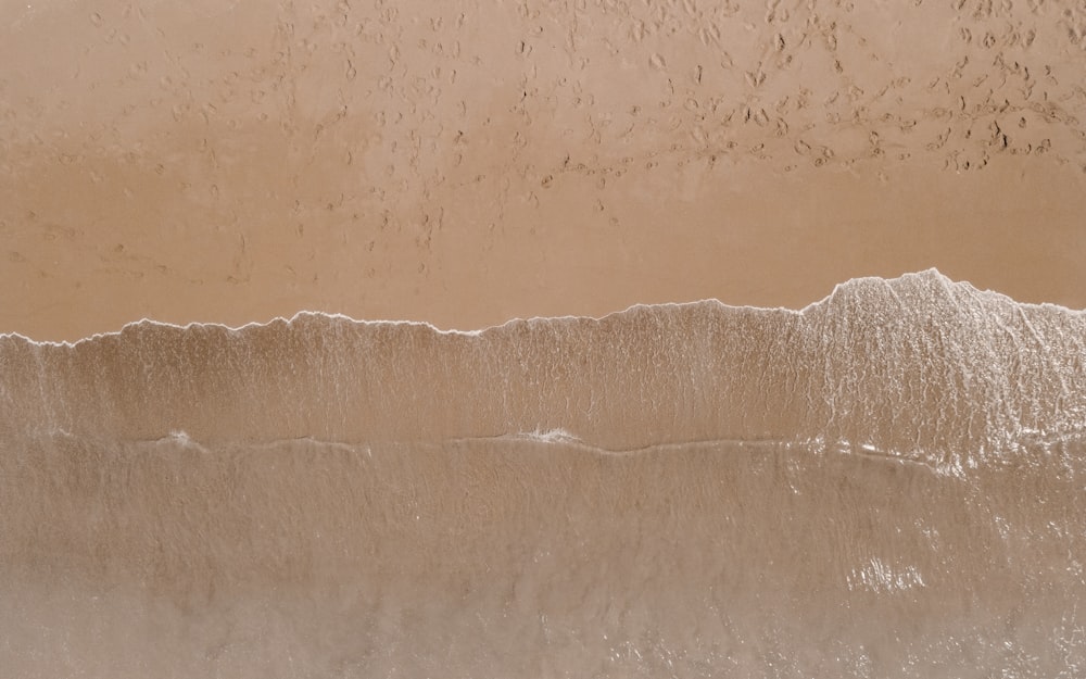 an aerial view of a sandy beach with waves