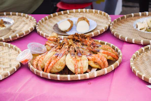 Close-up of succulent shrimp piled neatly in a basket with green leaves.