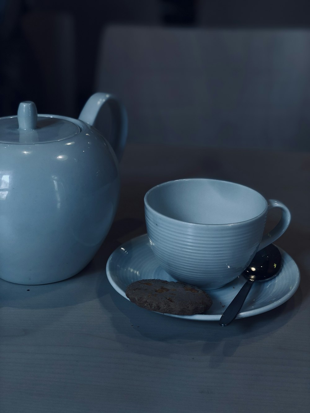 a tea pot and a plate with a cookie on it