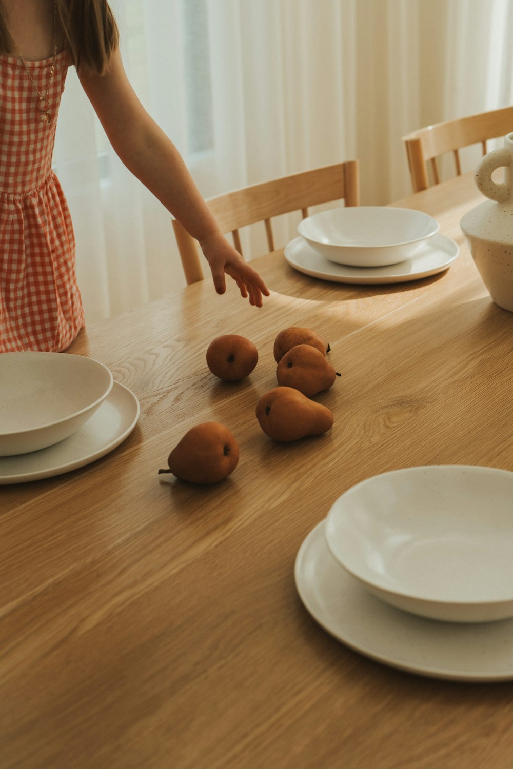 a little girl reaching for some fruit on a table