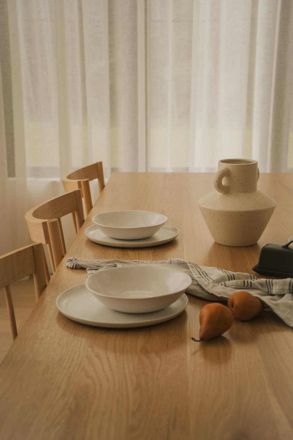 a wooden table topped with white plates and bowls