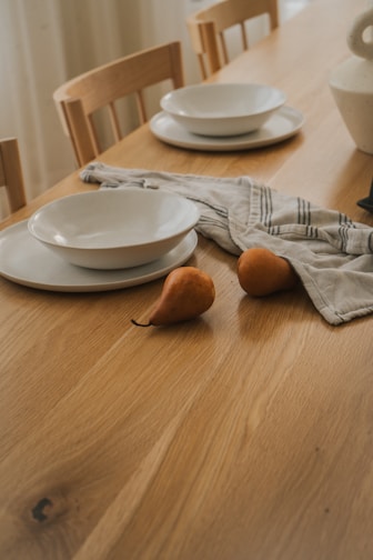 A minimalist dining table set with ceramic plates and a centerpiece of fresh eucalyptus branches.