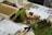A collection of terrarium-making materials is arranged on a table, including a tray filled with soil, pieces of moss, various sizes of stones, and gardening tools. Sheets with printed text and images are partially obscured by the items, suggesting instructions or guidelines.