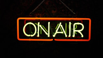 a neon sign that says on air hanging from a chain