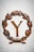 A large rusty metal letter Y is encircled by a laurel wreath made of the same material. The wreath features detailed leaves and is placed on a light marble surface, giving a classic and antiquated appearance.