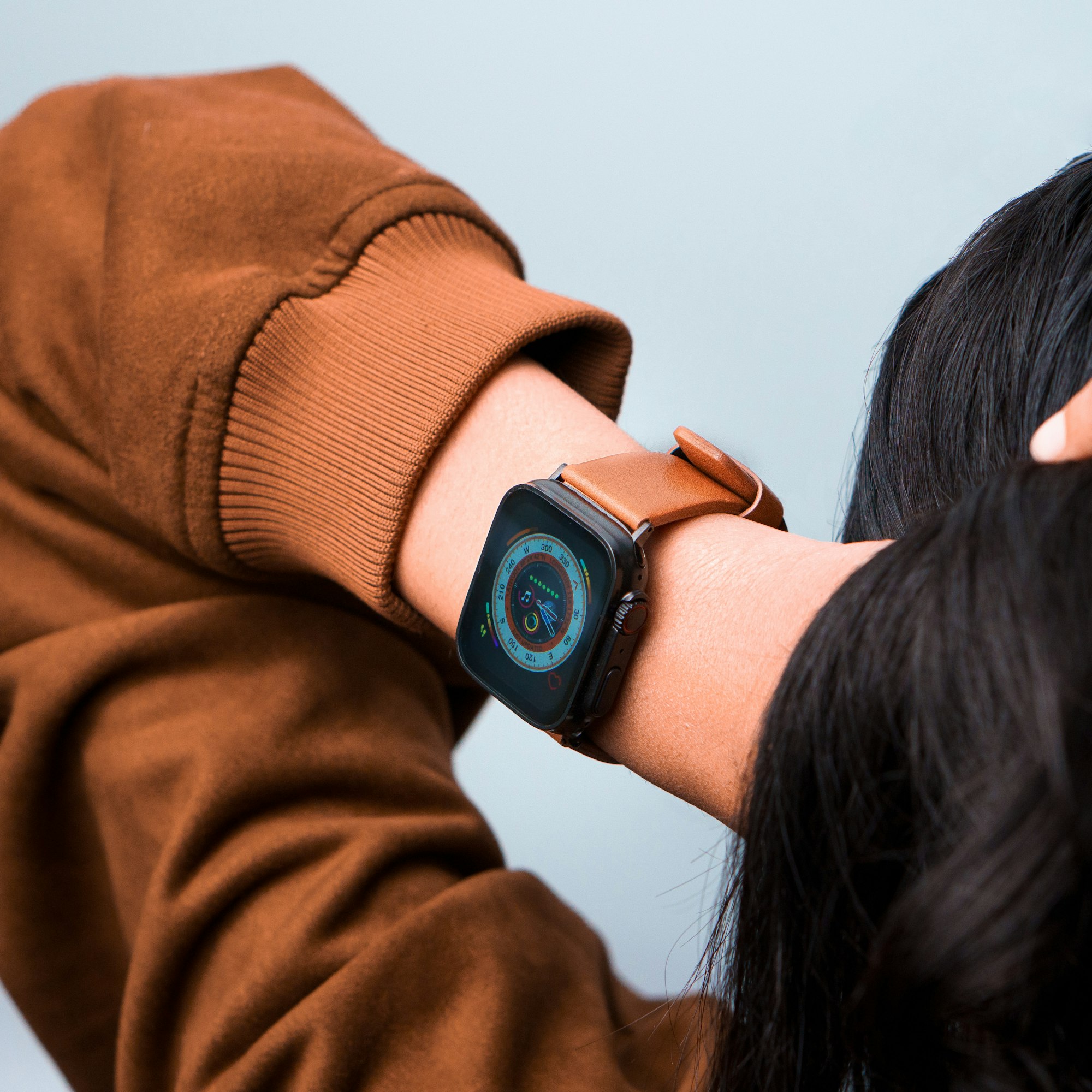 Pessoa de costas com o braço esquerdo em destaque a mexer no cabelo e com um Apple Watch Ultra no pulso.