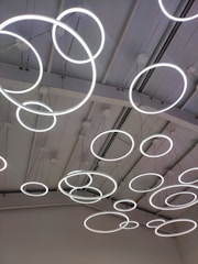 A ceiling with multiple circular LED light fixtures suspended at various heights, creating a modern and artistic appearance.
