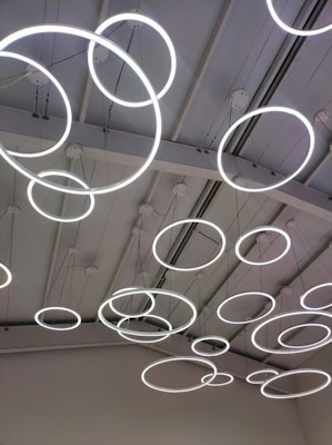 A ceiling with multiple circular LED light fixtures suspended at various heights, creating a modern and artistic appearance.