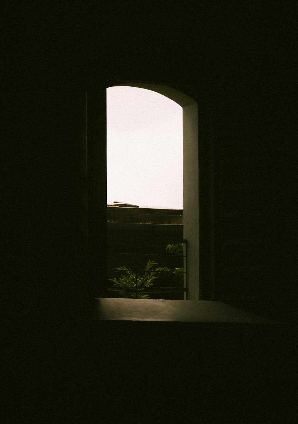 an open window in a dark room with a view of trees