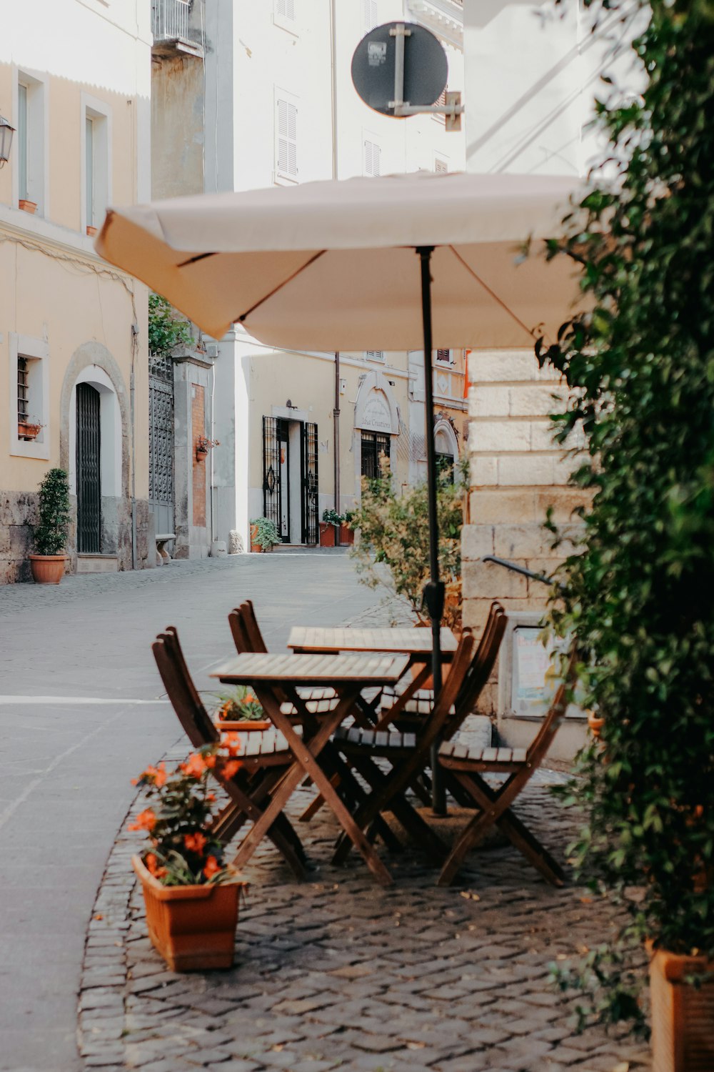 a table and chairs with an umbrella on a cobblestone street