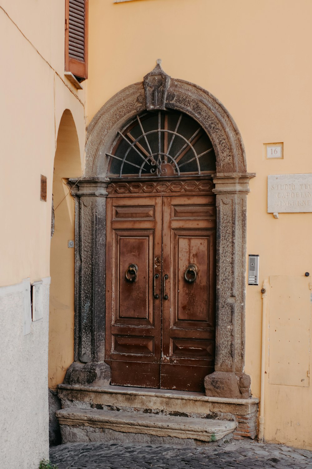 a large wooden door in front of a yellow building