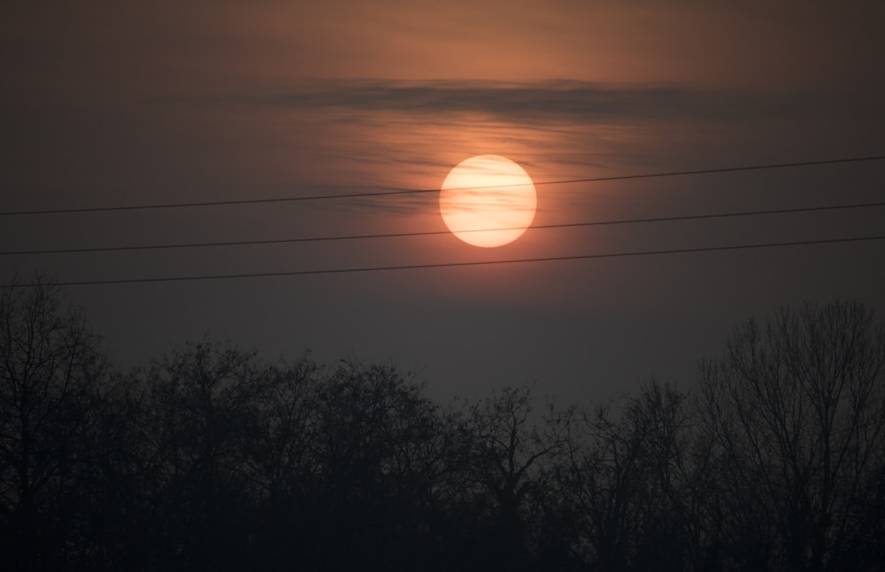 the sun is setting over the trees in the distance