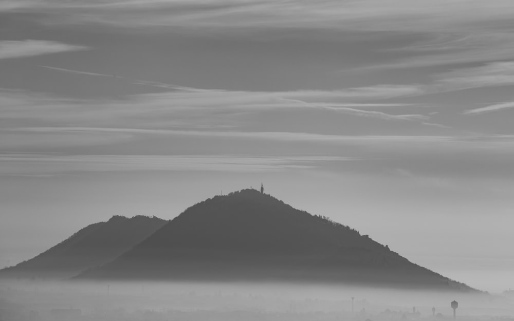 a black and white photo of a mountain in the fog