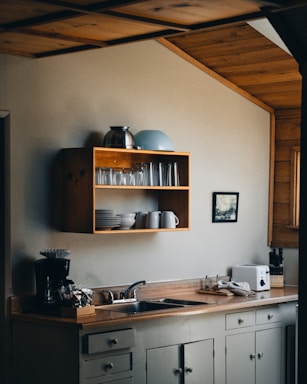 A cozy kitchen corner featuring a minimalist floating shelf with neatly arranged stainless steel flatware and a soft cotton tablecloth.