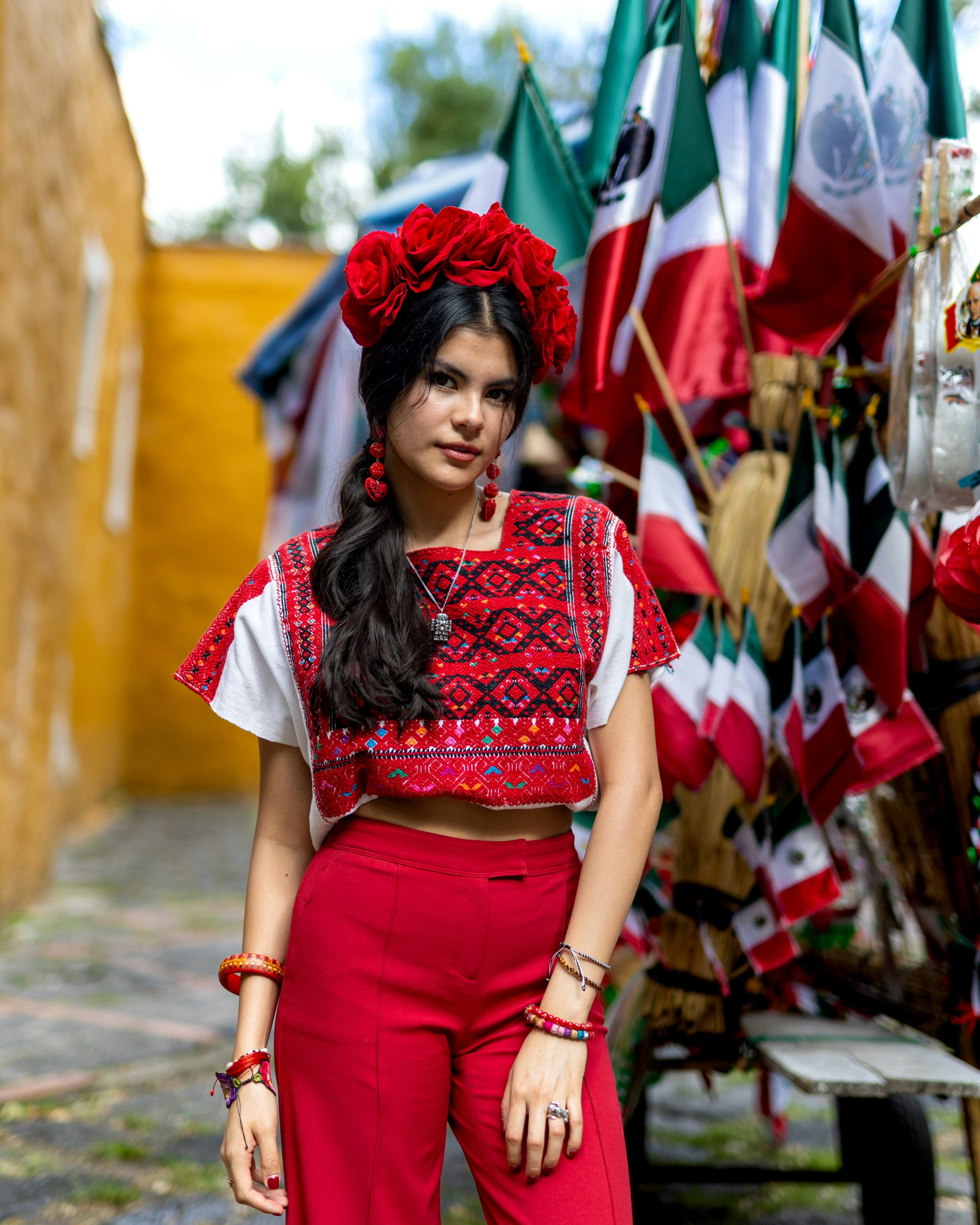a woman in a mexican outfit standing in front of a display of flags
