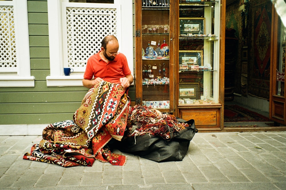 a man sitting on the ground in front of a store