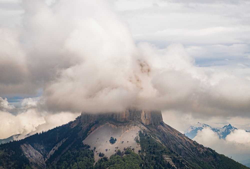 a mountain covered in clouds and trees on a cloudy day