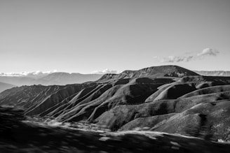 A panoramic view of rolling hills and distant mountains under soft evening light.
