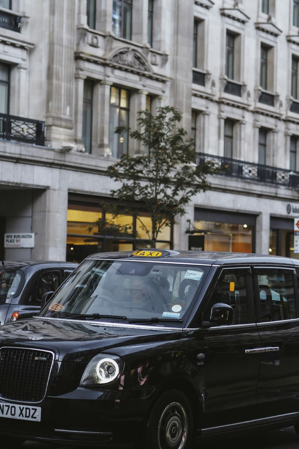 a black taxi cab driving down a street next to tall buildings