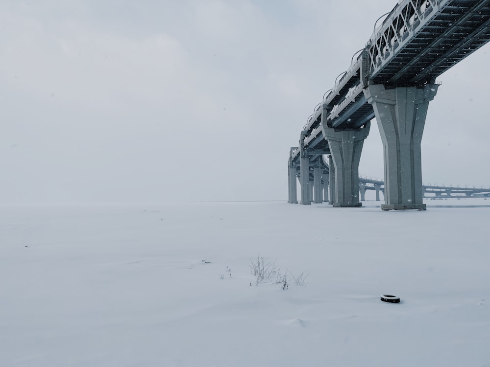 a snow covered field with a bridge in the background