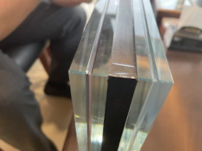 Close-up of a skilled technician carefully cutting a large glass pane with precision tools