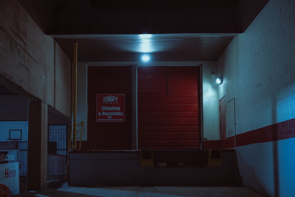 a dark hallway with a red door and a red and white sign