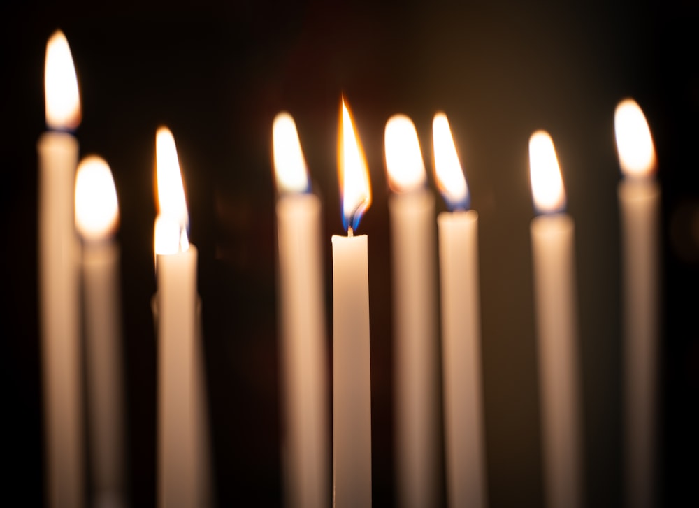 a group of white candles with one lit in the middle