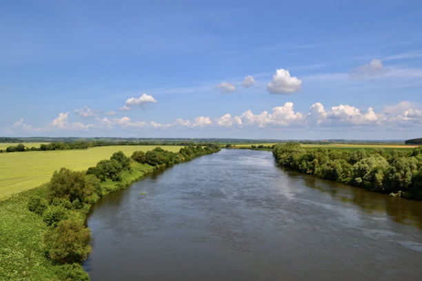A serene river winding through a lush green watershed under a clear blue sky.