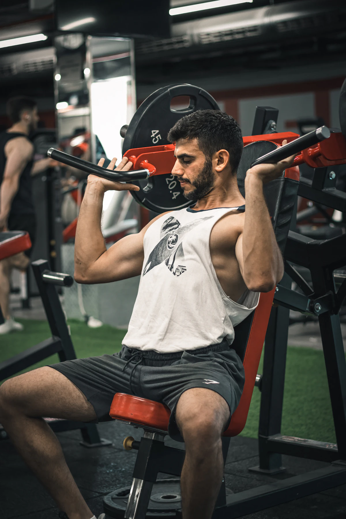 Young man in athletic clothes sitting on a gym bench next to a barbell, considering whether testosterone therapy makes sense in his early thirties.