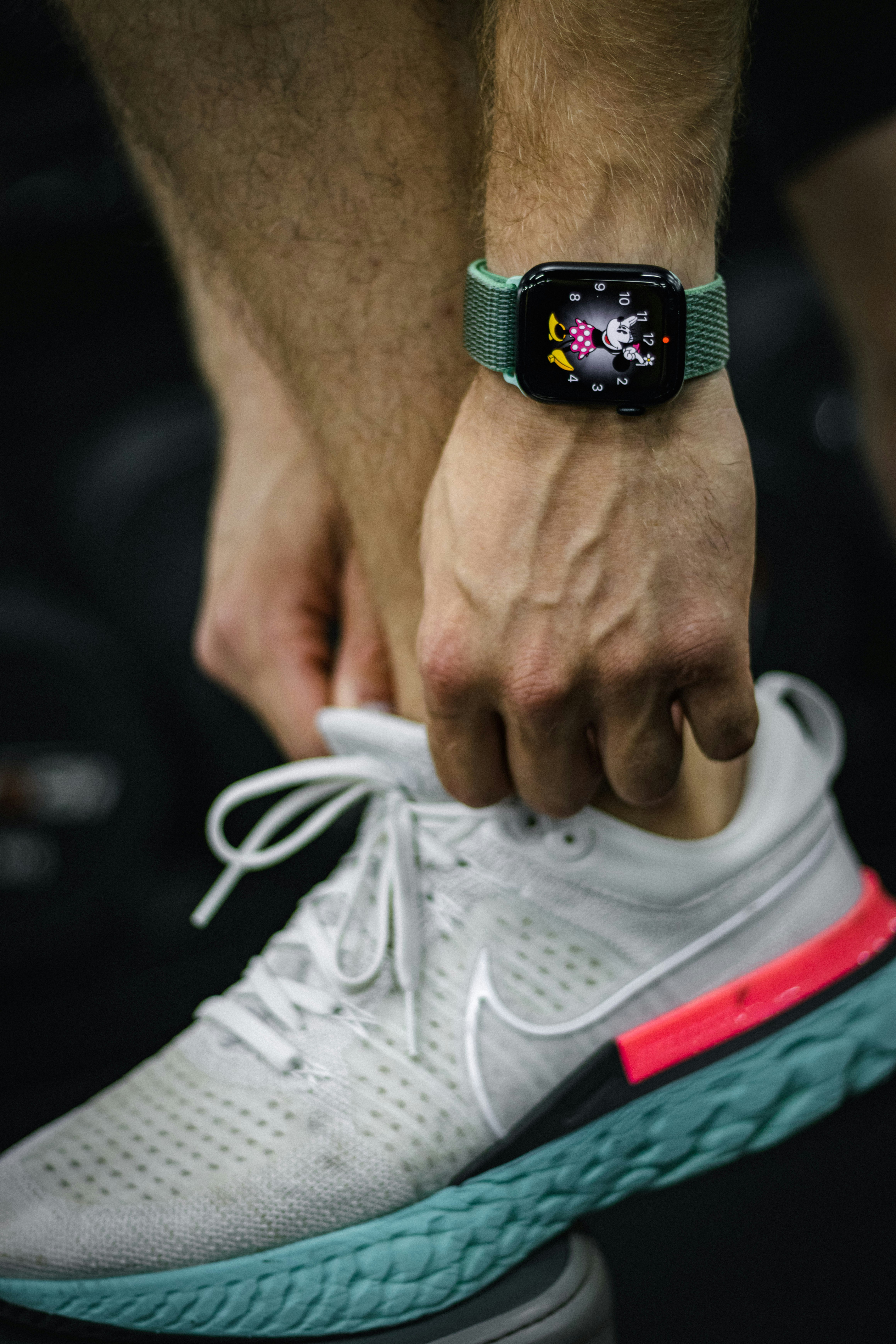 Athletic man tying laces on white running shoes, bright gym environment, natural light