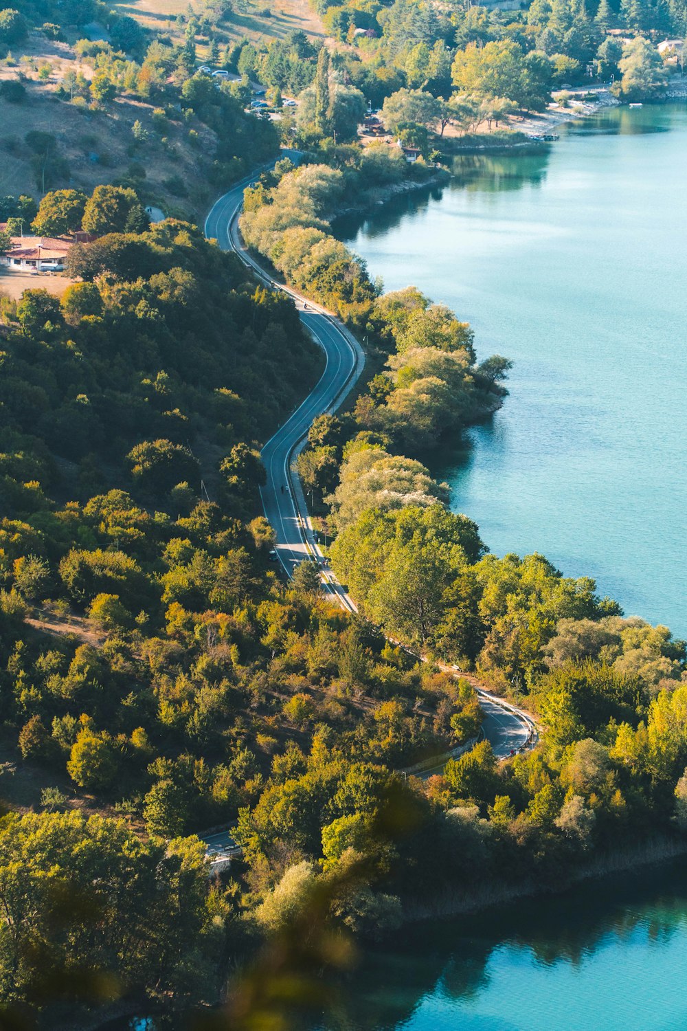 an aerial view of a winding road near a lake