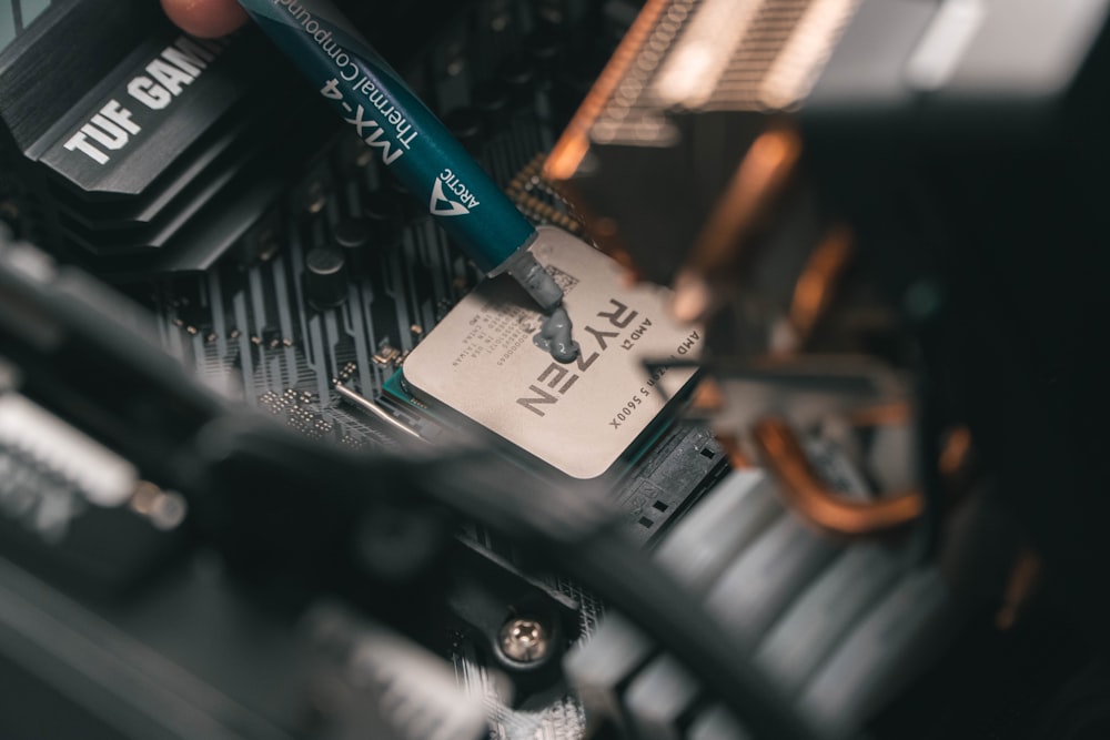 a close up of a person holding a pen near a computer motherboard