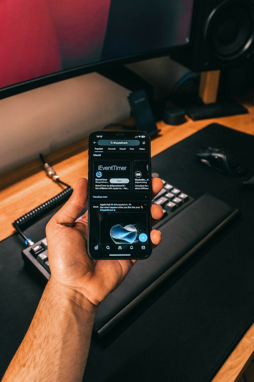 a person holding a cell phone in front of a computer