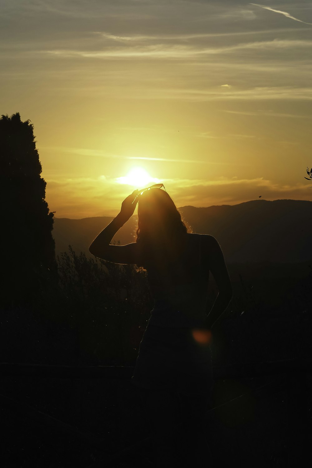 a woman standing in the sun with her hands on her head