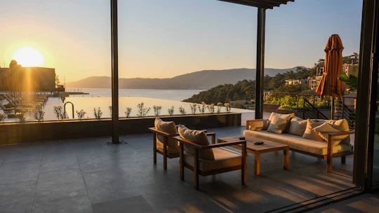 Peaceful outdoor seating area surrounded by lush greenery and lake views at sunset.