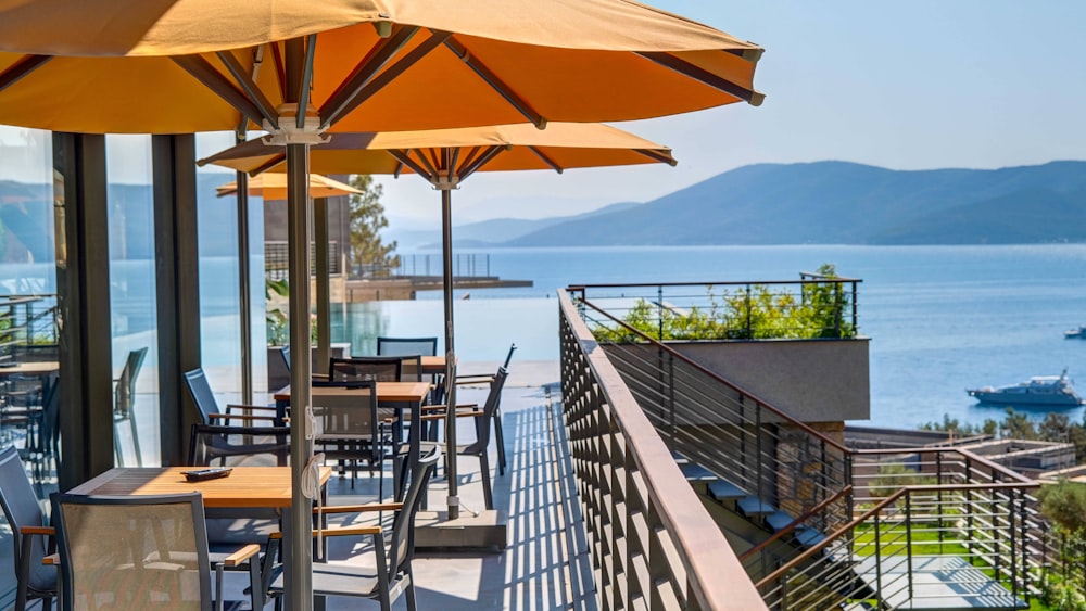 a restaurant with tables and umbrellas overlooking the water