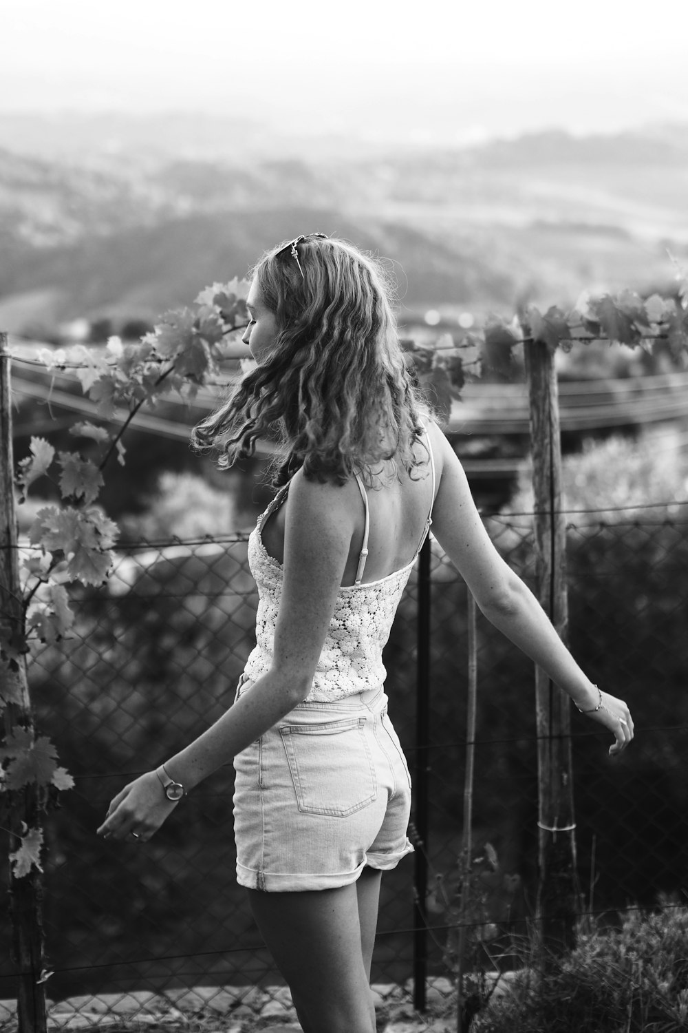 a woman in a white dress standing next to a fence