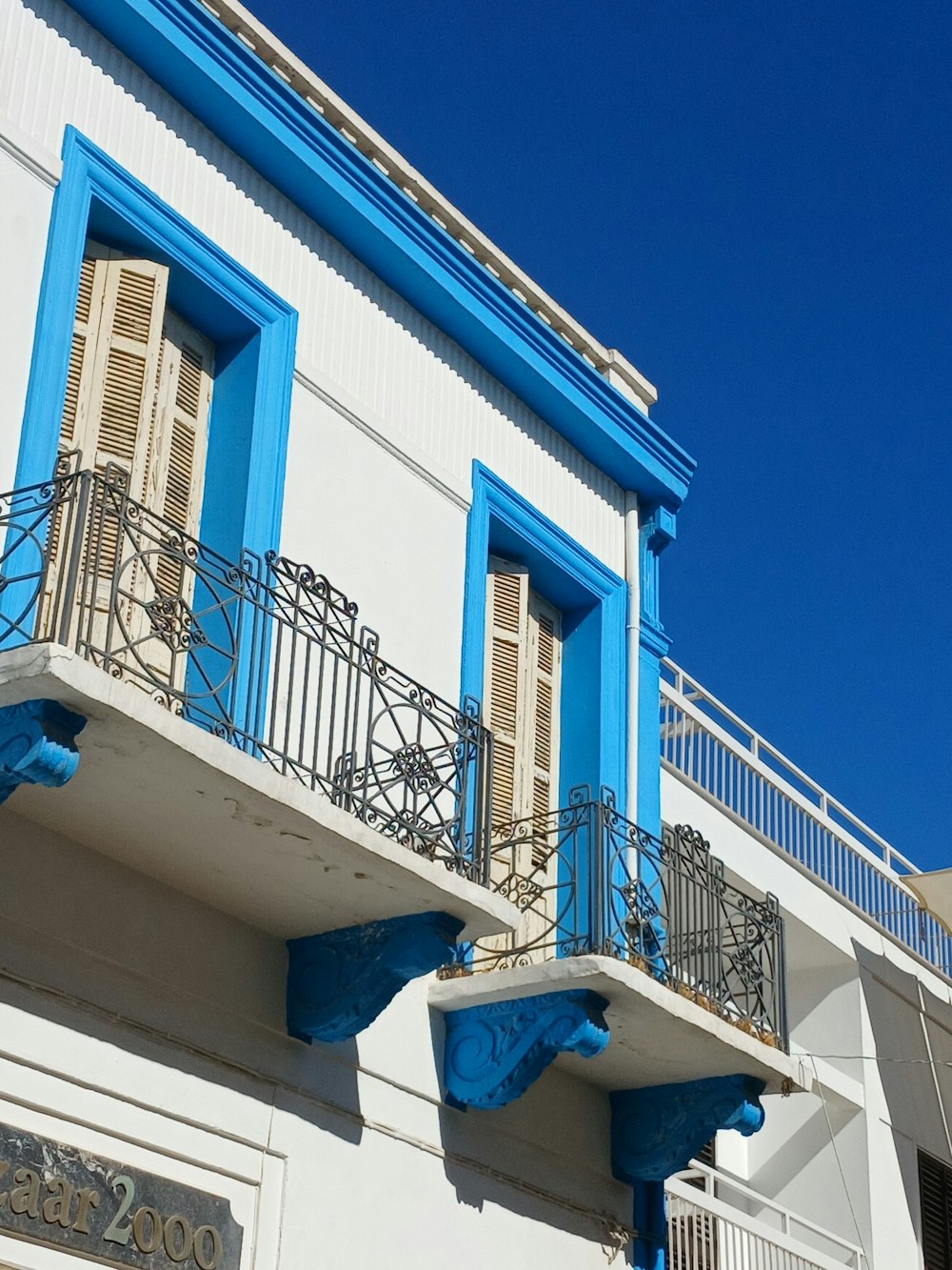 un bâtiment bleu et blanc avec balcons et volets