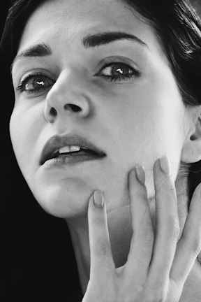 A close-up shot of a person holding their chin with their hand. The expression appears thoughtful or introspective.
