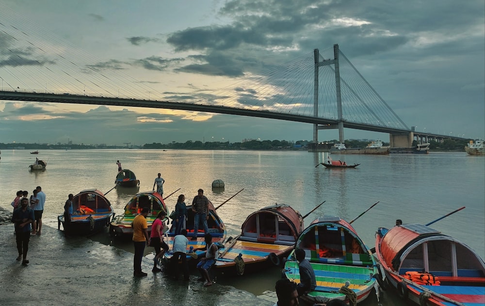 Un grupo de barcos sentados en la cima de un río junto a un puente