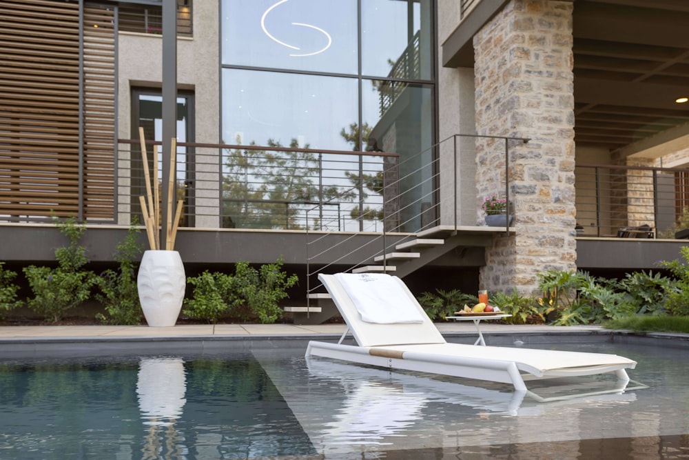 a white lounge chair sitting next to a swimming pool