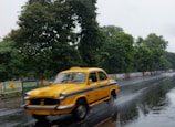 A taxi speeding through a rain-soaked urban road with reflections on the pavement