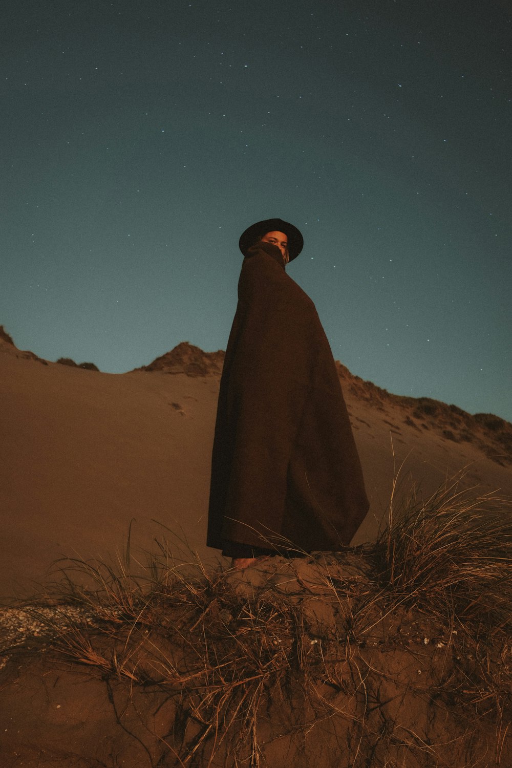 砂漠に立つ黒いマントを着た男