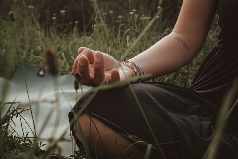 a woman is sitting in the grass with her hand on the ground