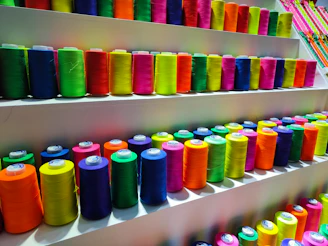 Close-up of colorful 3D printer filament spools arranged neatly on a shelf.