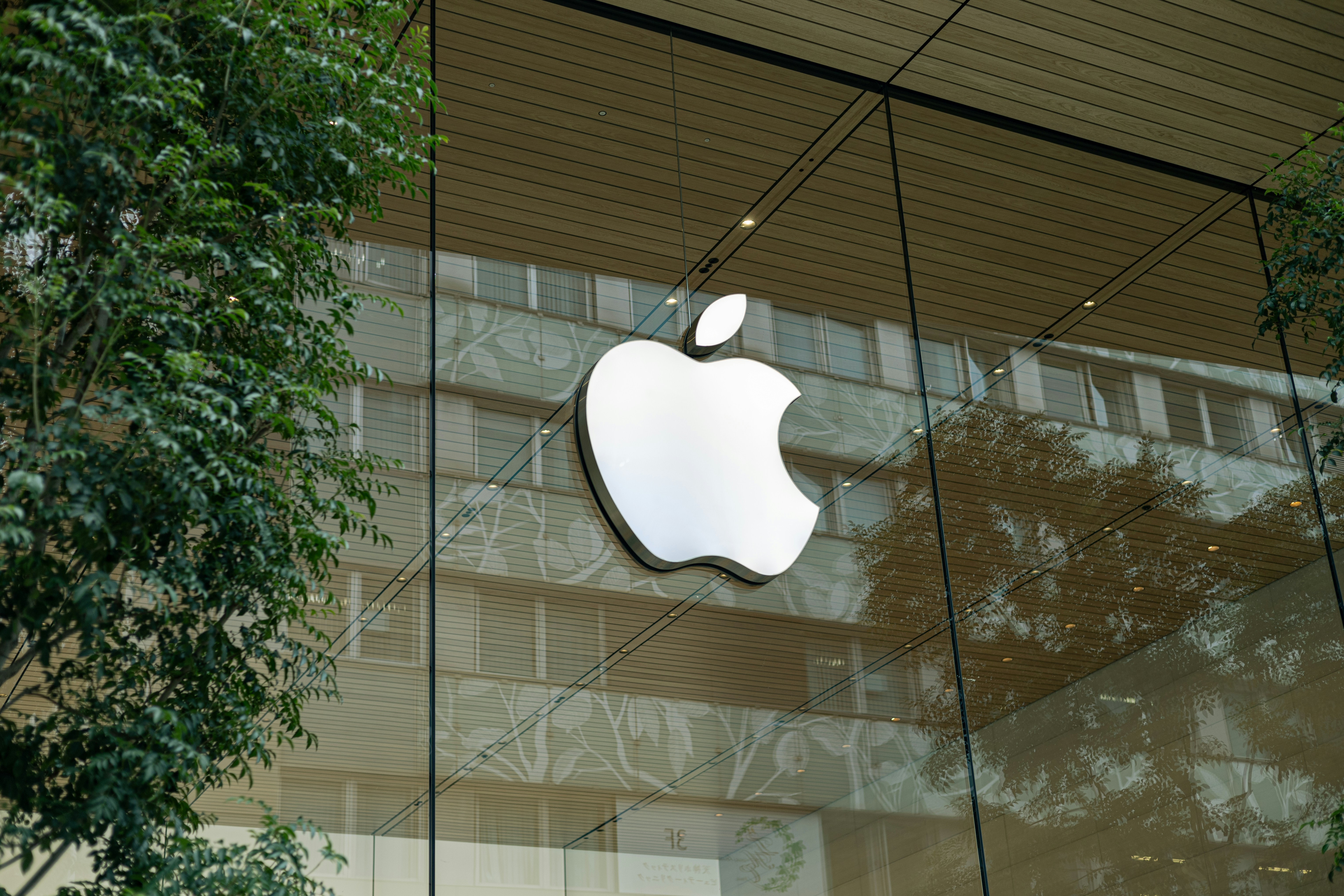 the apple logo is reflected in the glass of a building