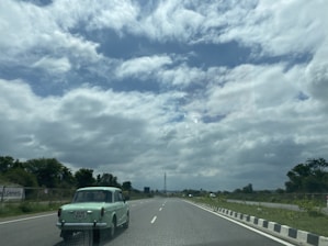 A spacious car cruising on a highway with lush greenery on both sides.